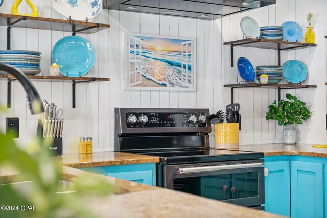 kitchen with blue cabinetry, sink, stainless steel appliances, and wall chimney range hood