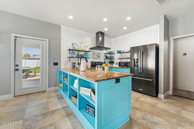 kitchen featuring blue cabinetry, sink, wall chimney exhaust hood, high end refrigerator, and kitchen peninsula