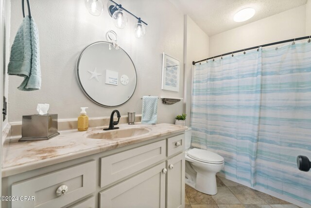 bathroom with vanity, tile patterned floors, a shower with shower curtain, toilet, and a textured ceiling