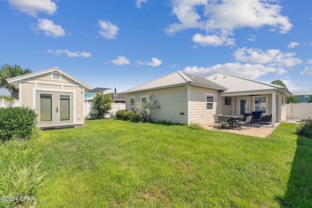 rear view of property with french doors, a yard, ceiling fan, and a patio area