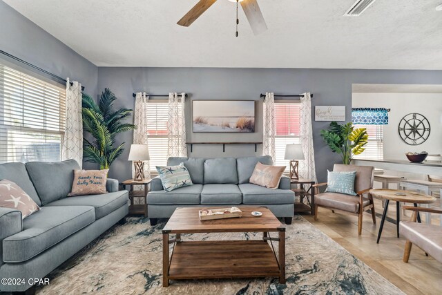 tiled living room with ceiling fan and a textured ceiling