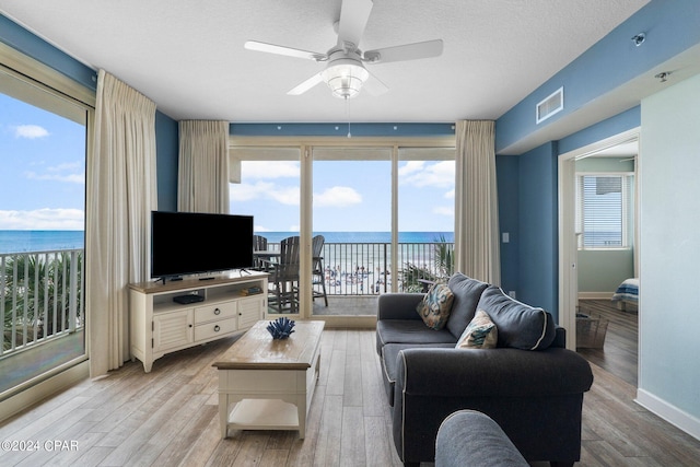 living room with ceiling fan, light hardwood / wood-style floors, and a textured ceiling