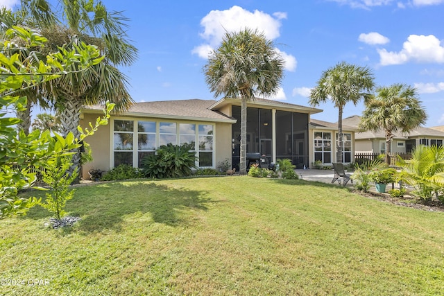 back of house featuring a lawn, a sunroom, and stucco siding