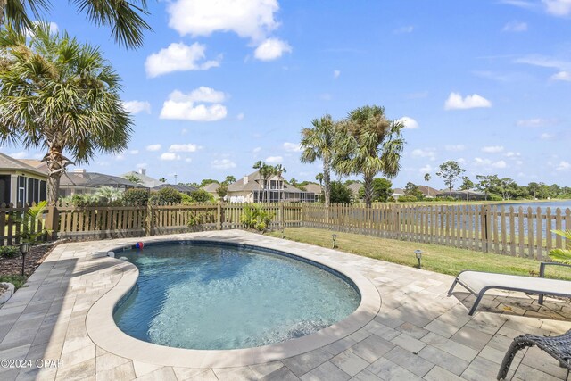 view of pool with a water view, a lawn, and a patio area