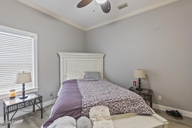 bedroom featuring baseboards, visible vents, crown molding, and wood finished floors