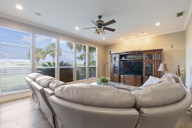 living room with ornamental molding, visible vents, light wood-style floors, and a ceiling fan