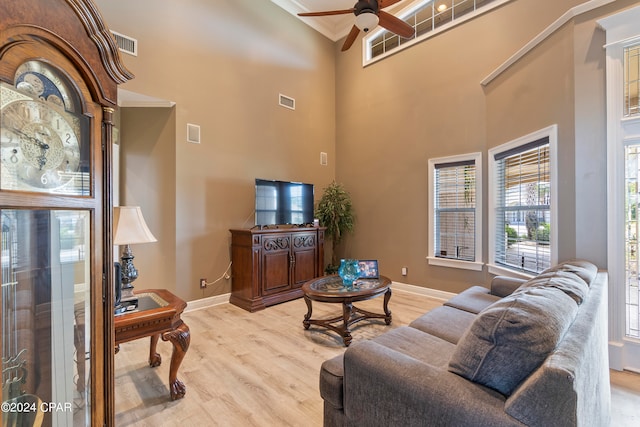 living room featuring a high ceiling, ceiling fan, and light hardwood / wood-style floors