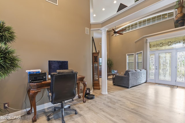 home office featuring baseboards, a high ceiling, wood finished floors, and ornate columns