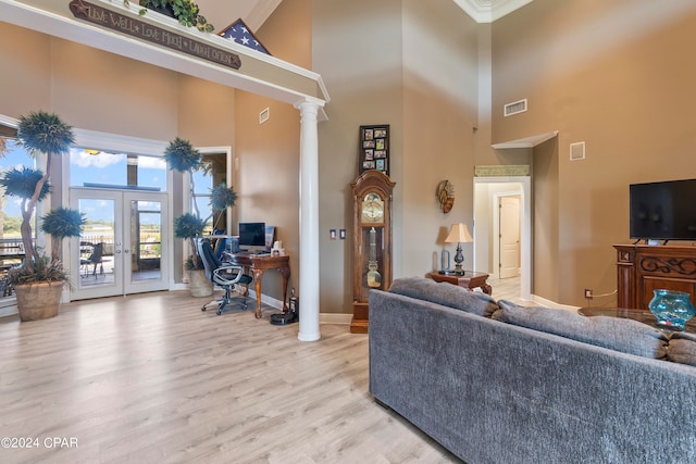 living room featuring light hardwood / wood-style floors, a high ceiling, french doors, and ornate columns