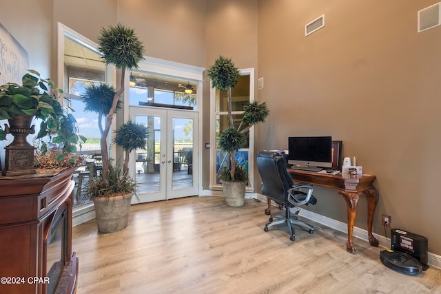 office featuring french doors, light hardwood / wood-style flooring, and a high ceiling