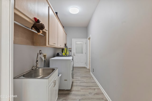 laundry room featuring washing machine and clothes dryer, cabinets, sink, and light hardwood / wood-style floors