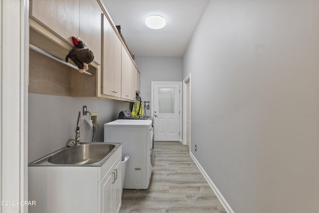 washroom with cabinet space, baseboards, washer and clothes dryer, light wood-type flooring, and a sink