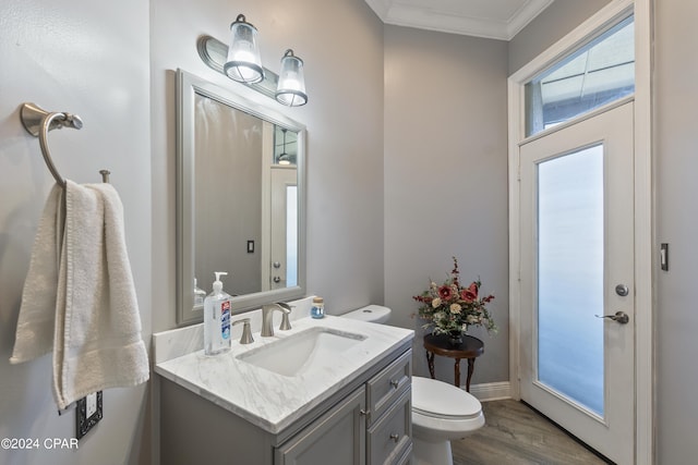 bathroom featuring toilet, wood finished floors, vanity, baseboards, and ornamental molding