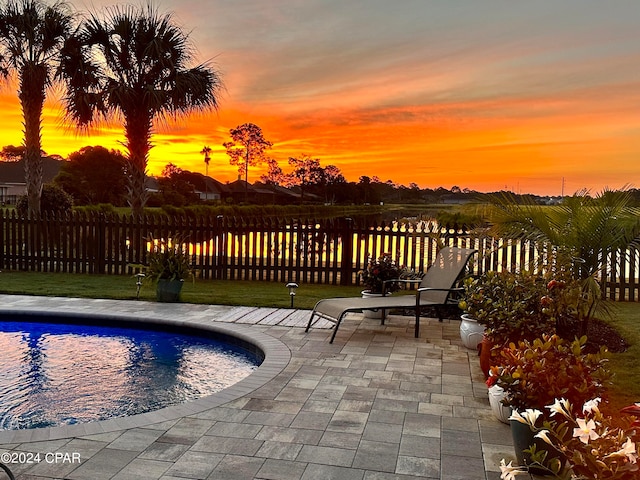 pool at dusk featuring a patio area