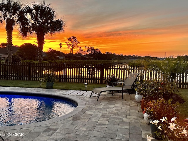 pool at dusk featuring a fenced in pool, a patio area, and fence