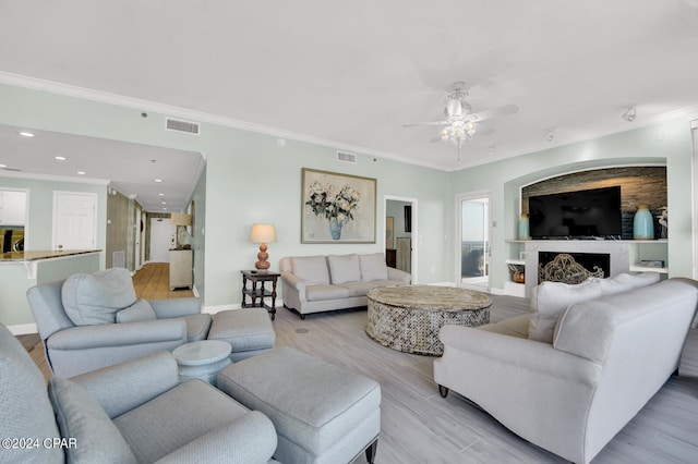 living room with crown molding, light hardwood / wood-style flooring, and ceiling fan