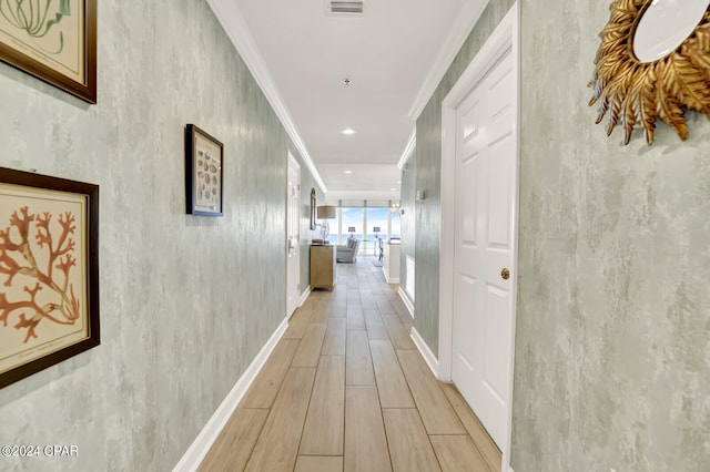 hallway featuring ornamental molding and light hardwood / wood-style floors