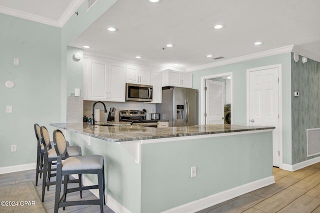 kitchen featuring stone counters, stainless steel appliances, light wood-type flooring, and white cabinets