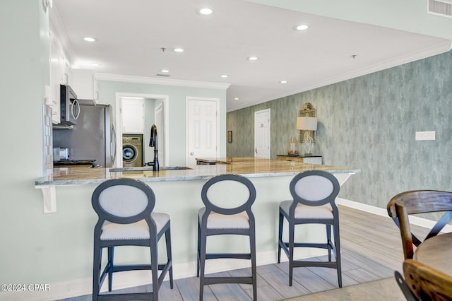 kitchen with light wood-type flooring, appliances with stainless steel finishes, white cabinetry, and kitchen peninsula