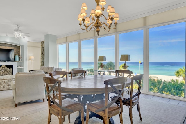 dining room featuring ceiling fan with notable chandelier, a view of the beach, a water view, and light hardwood / wood-style floors