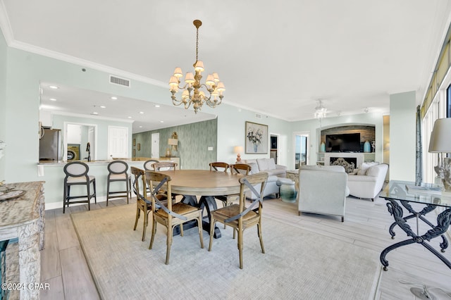 dining room featuring light hardwood / wood-style flooring, ornamental molding, ceiling fan with notable chandelier, and sink