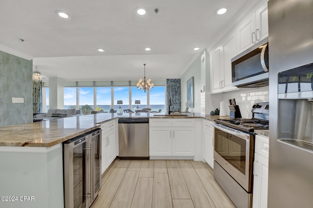 kitchen featuring appliances with stainless steel finishes, white cabinetry, an inviting chandelier, and kitchen peninsula