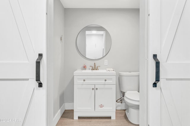 bathroom with toilet, baseboards, wood finished floors, and vanity