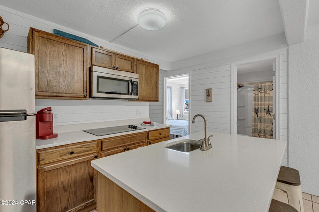 kitchen with a kitchen breakfast bar, stainless steel appliances, a center island with sink, and sink