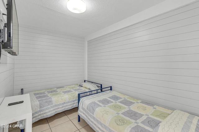 tiled bedroom featuring a textured ceiling and wooden walls