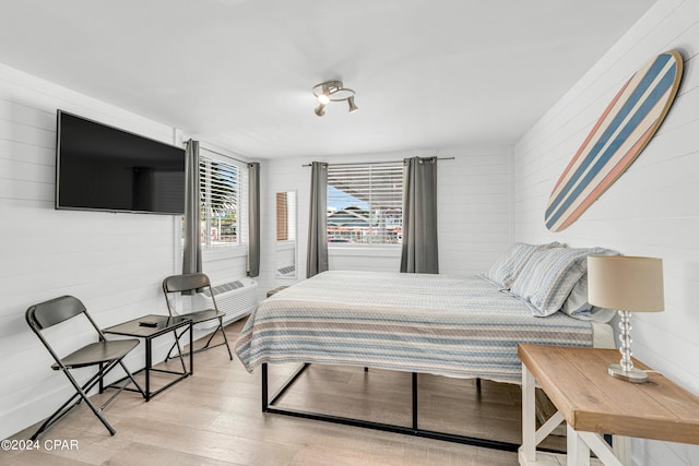 bedroom with a wall mounted air conditioner and light hardwood / wood-style flooring