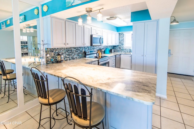 kitchen with pendant lighting, a breakfast bar area, stainless steel appliances, and white cabinets