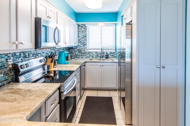 kitchen featuring white cabinetry, tasteful backsplash, sink, appliances with stainless steel finishes, and light tile patterned flooring