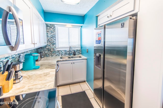 kitchen featuring a textured ceiling, backsplash, appliances with stainless steel finishes, sink, and white cabinetry