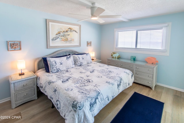 bedroom with ceiling fan, a textured ceiling, and light hardwood / wood-style flooring