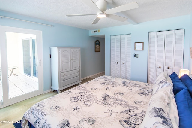 bedroom featuring multiple closets, a textured ceiling, light hardwood / wood-style flooring, and ceiling fan