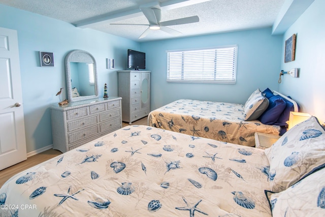 bedroom with ceiling fan, light hardwood / wood-style floors, and a textured ceiling