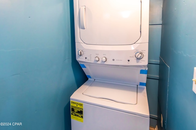 laundry room with water heater and stacked washing maching and dryer