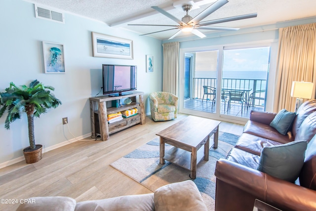 living room with a textured ceiling, light hardwood / wood-style flooring, and ceiling fan