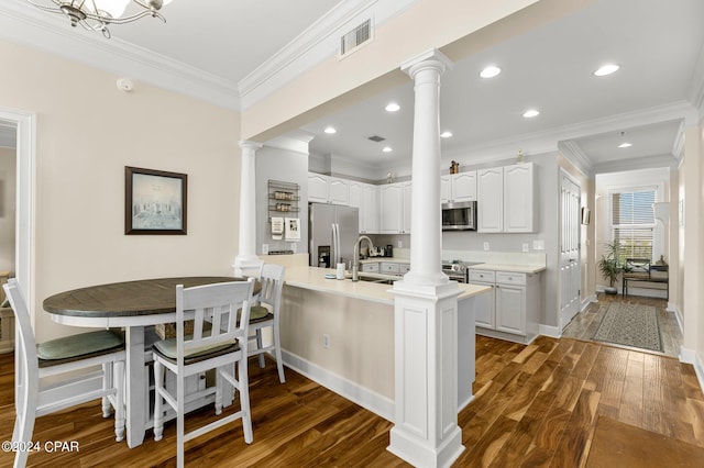 kitchen with appliances with stainless steel finishes, kitchen peninsula, white cabinetry, and dark wood-type flooring