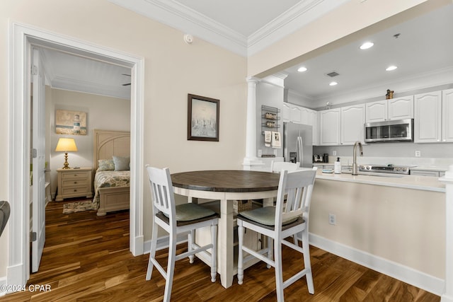 dining space featuring decorative columns, ornamental molding, and dark wood-type flooring