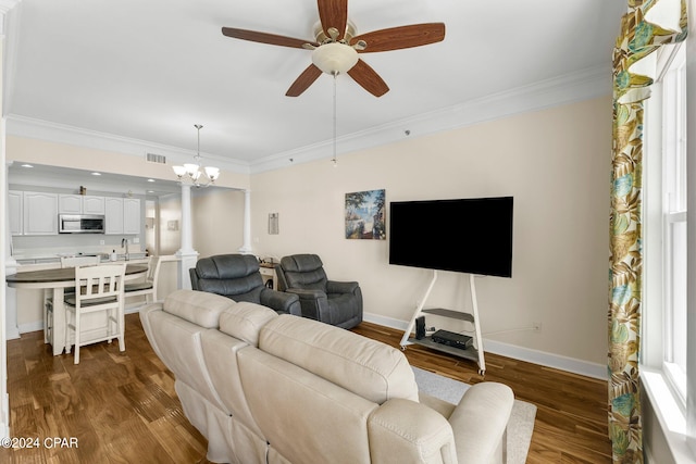 living room with ceiling fan with notable chandelier, dark hardwood / wood-style floors, sink, and crown molding