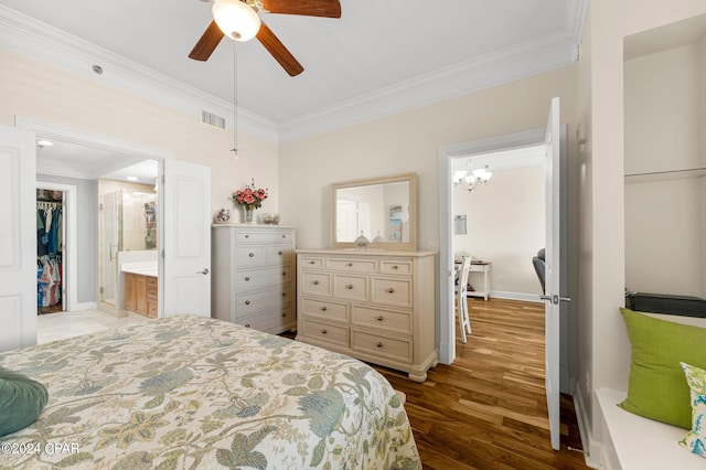 bedroom featuring light wood-type flooring, connected bathroom, a walk in closet, ceiling fan with notable chandelier, and crown molding