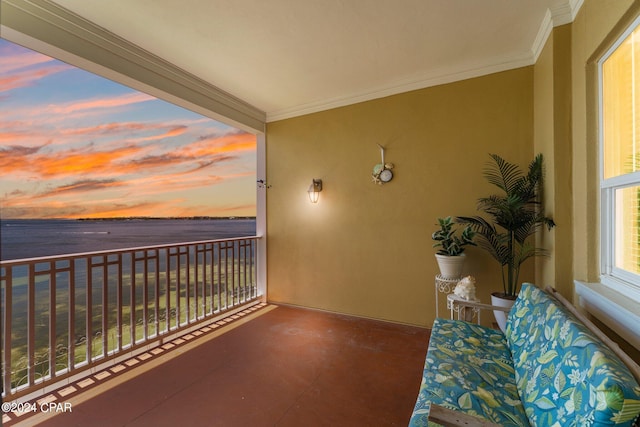 balcony at dusk featuring a water view