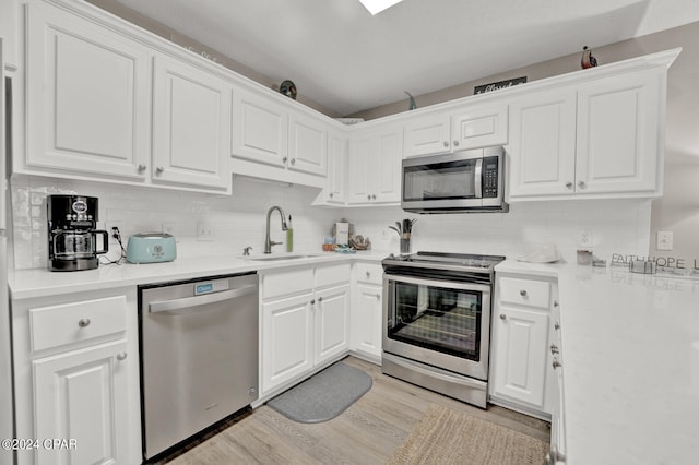 kitchen featuring sink, light hardwood / wood-style flooring, backsplash, white cabinetry, and appliances with stainless steel finishes