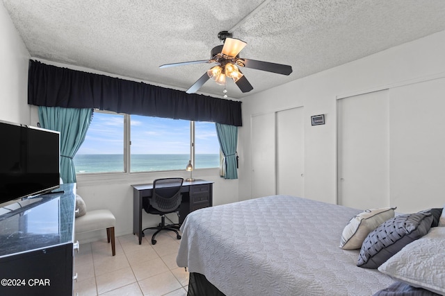 23223 Front Beach Rd Unit Ph-06, Panama City Beach, FL 32413 - bedroom featuring two closets, a water view, tile patterned flooring, ceiling fan, and a textured ceiling