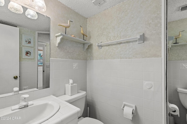 23223 Front Beach Rd Unit Ph-06, Panama City Beach, FL 32413 - bathroom with toilet, a textured ceiling, tile walls, vanity, and wainscoting