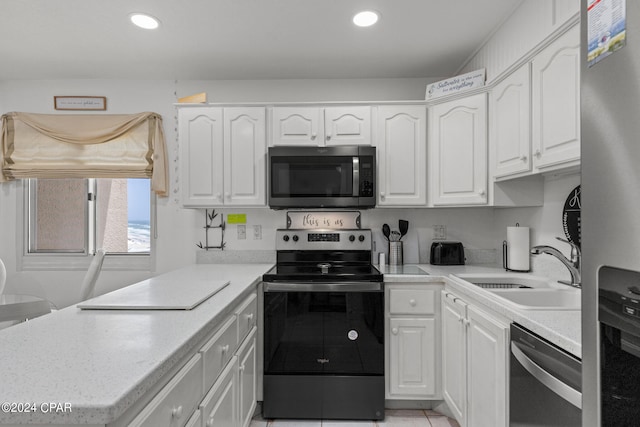 kitchen with appliances with stainless steel finishes, white cabinetry, light tile patterned floors, and sink