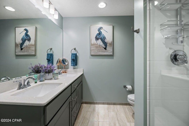 bathroom featuring hardwood / wood-style floors, walk in shower, toilet, vanity, and a textured ceiling