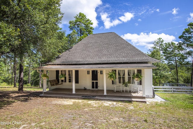 back of property with covered porch and a lawn