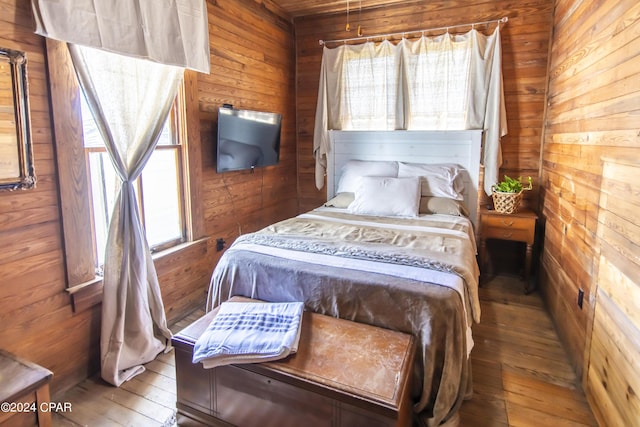 bedroom with hardwood / wood-style flooring and wooden walls